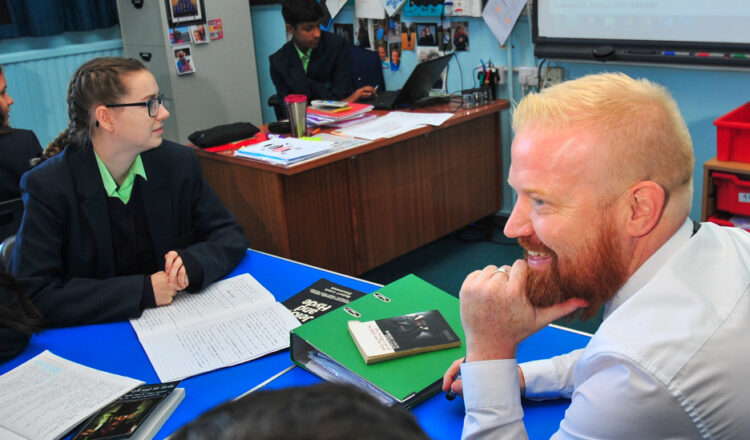 Ofsted examiner sitting with pupils in a classroom