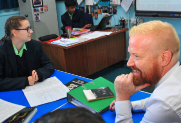 Ofsted examiner sitting with pupils in a classroom